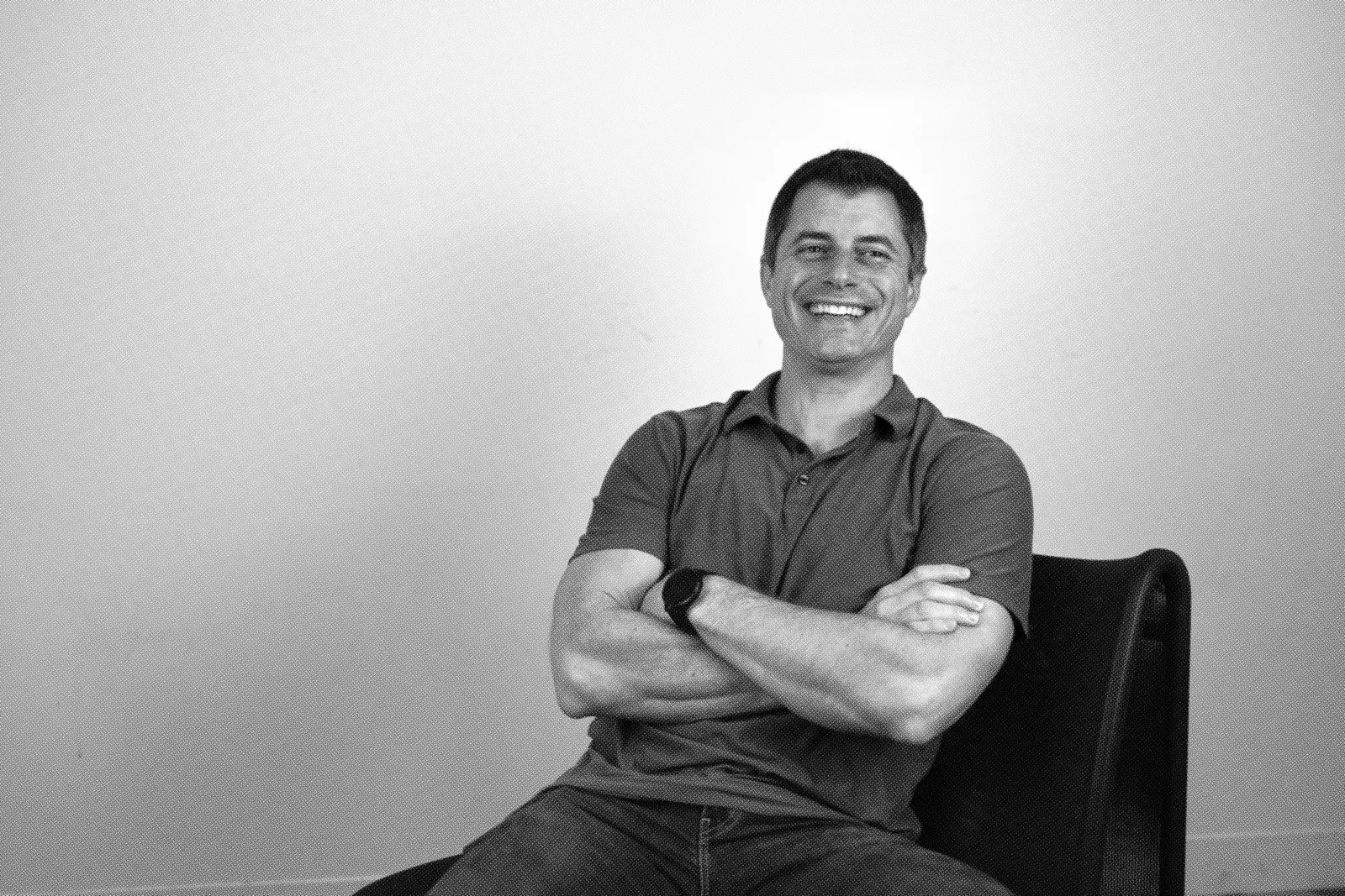 A member of the Cylake team seated with arms folded, laughing at the camera.